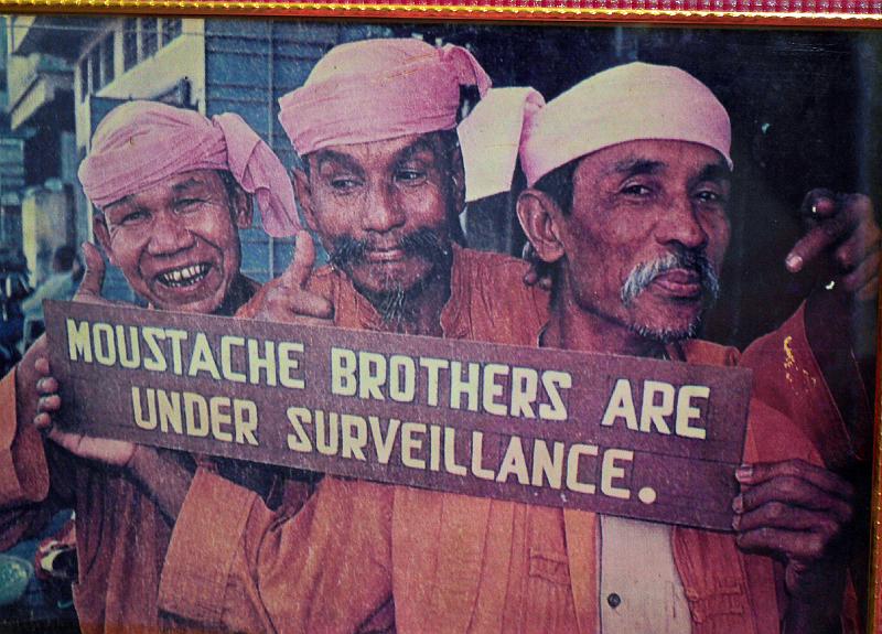 Burma III-059-Seib-2014.jpg - Old photo of the former political comedian troupe Moustache Brothers, from left cousin Lu Zaw and brothers Par Par Lay and Lu Maw. Leader Par Par Lay died in August 2013 (Photo of the photo by Roland Seib)
